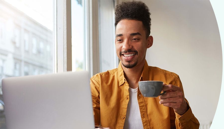 Webbplatskakor En man som dricker kaffe framför en dator
